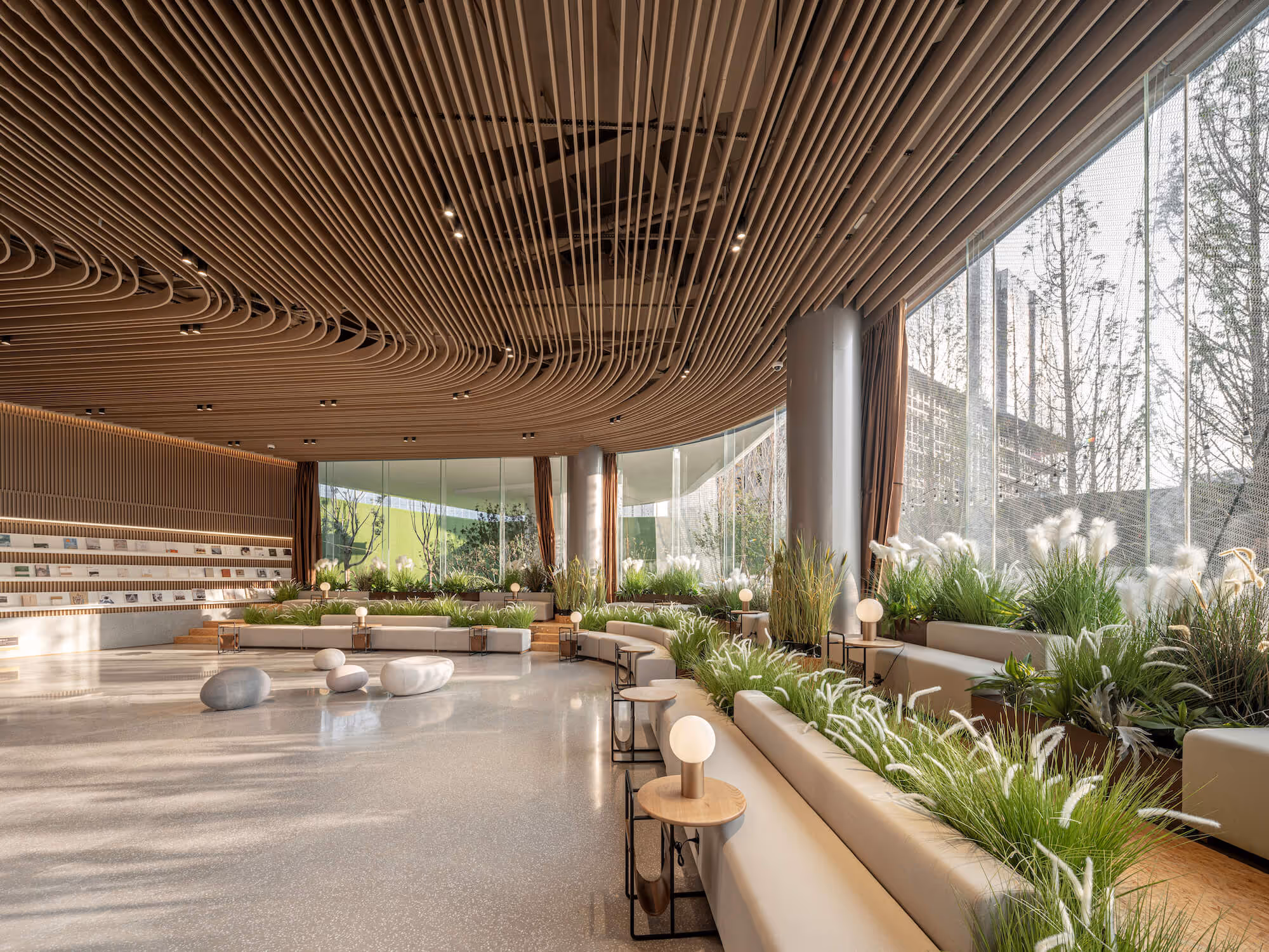 Modern spacious lounge with curved wooden ceiling, built-in seating, potted plants, and large floor-to-ceiling windows.