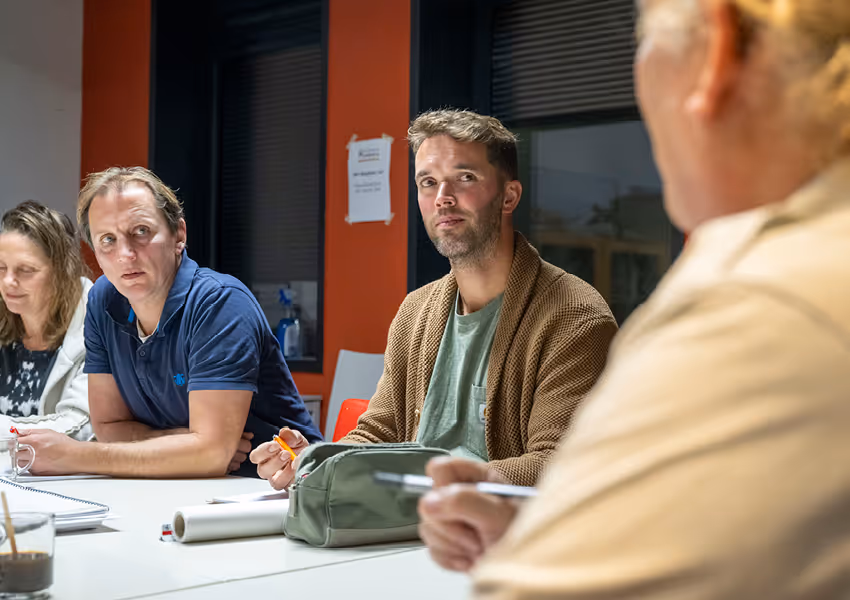 Three people sitting at a table engaged in a serious discussion during a meeting.