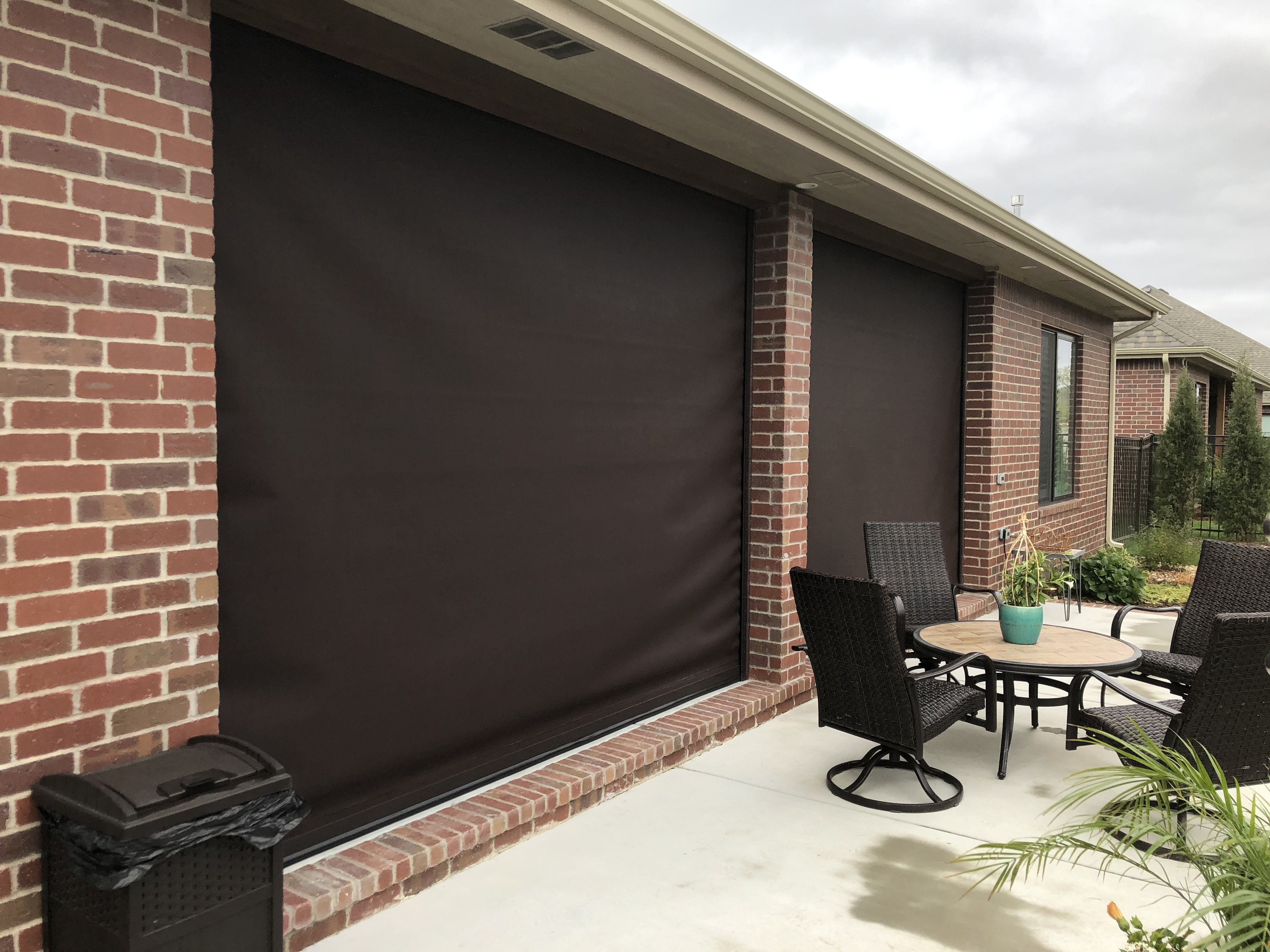 4 large brown patio shades installed on a back patio. 