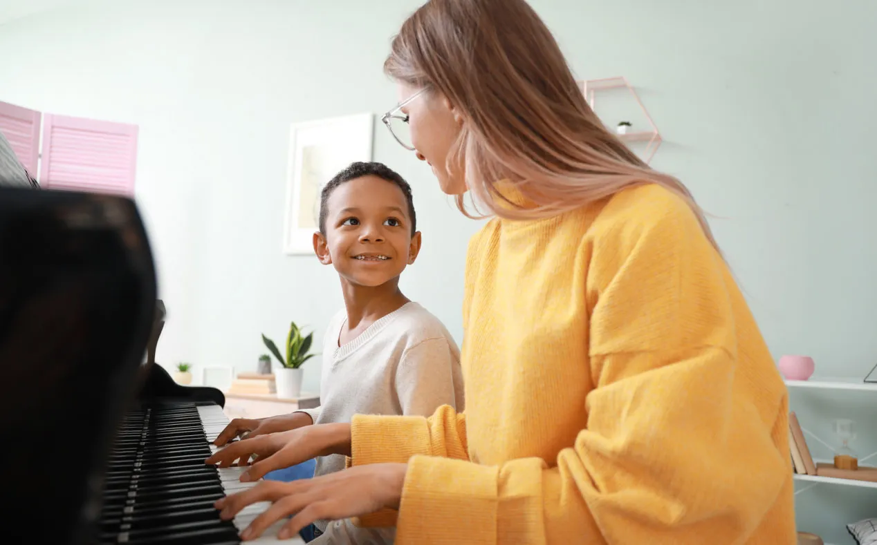 a woman and a boy are playing the piano