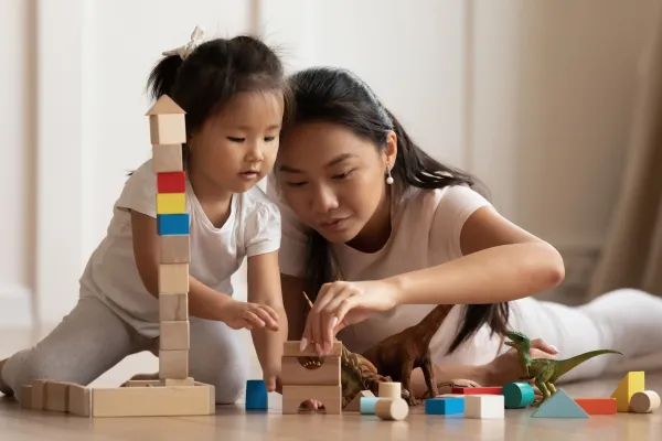 a woman and a child playing with wooden blocks