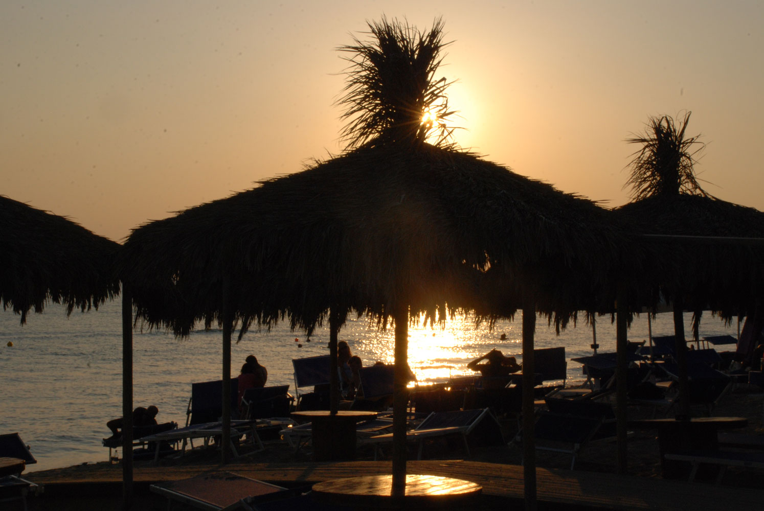 Tramonto tra ombrelloni di paglia sulla costa del Salento