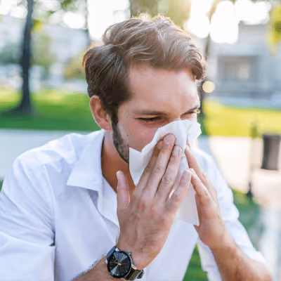 Man with sinus pain and congestion blowing his nose.