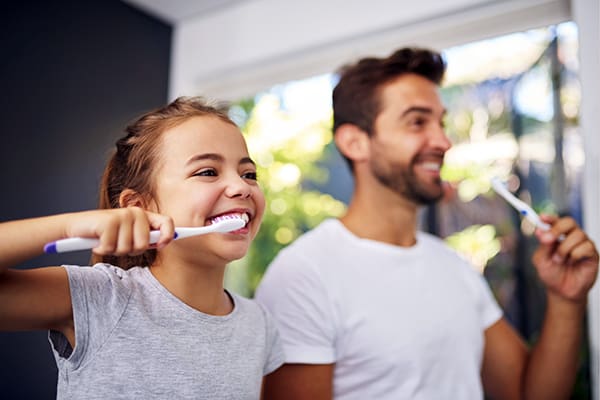 Dad and daughter brushing teeth together