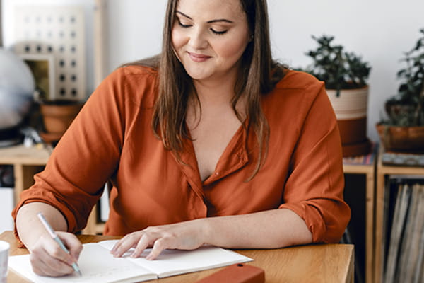 someone writing a to do list in a notebook