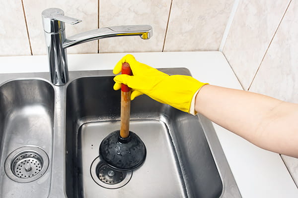 A plunger being used on a kitchen sink