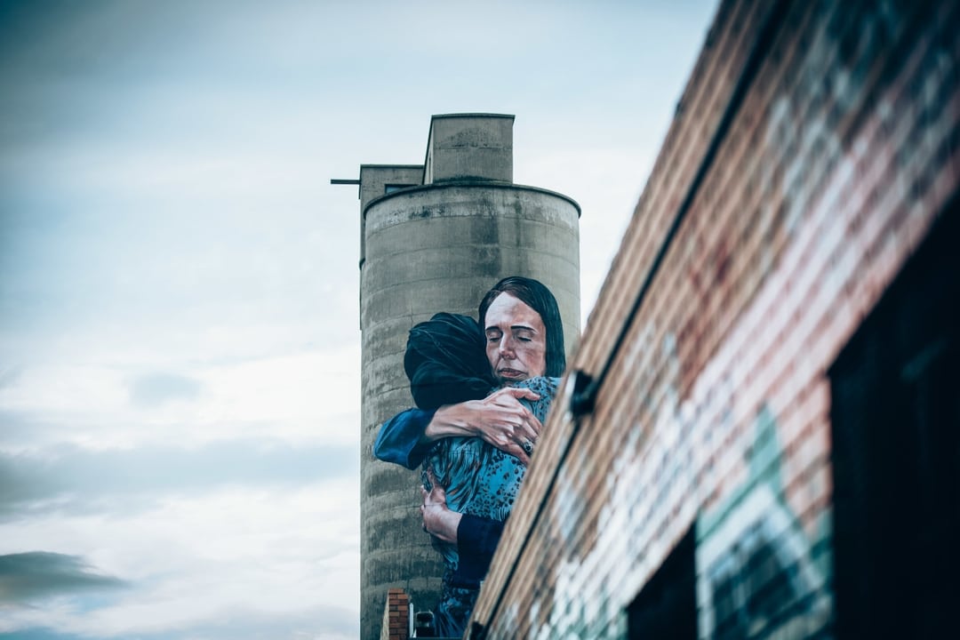 A silo with a mural on it showing two people hugging each other.