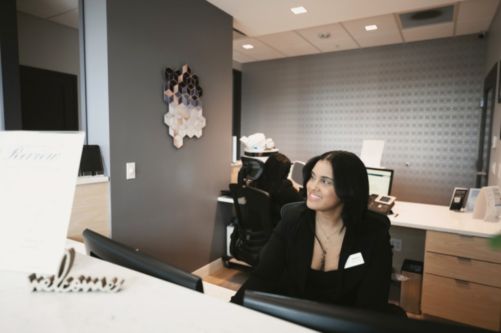 Receptionist at front desk smiling while working at computer