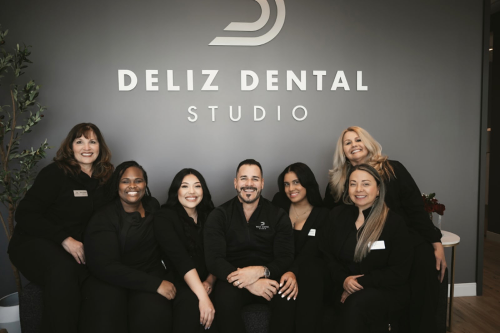 Deliz Dental Studio team of eight people posing together in office