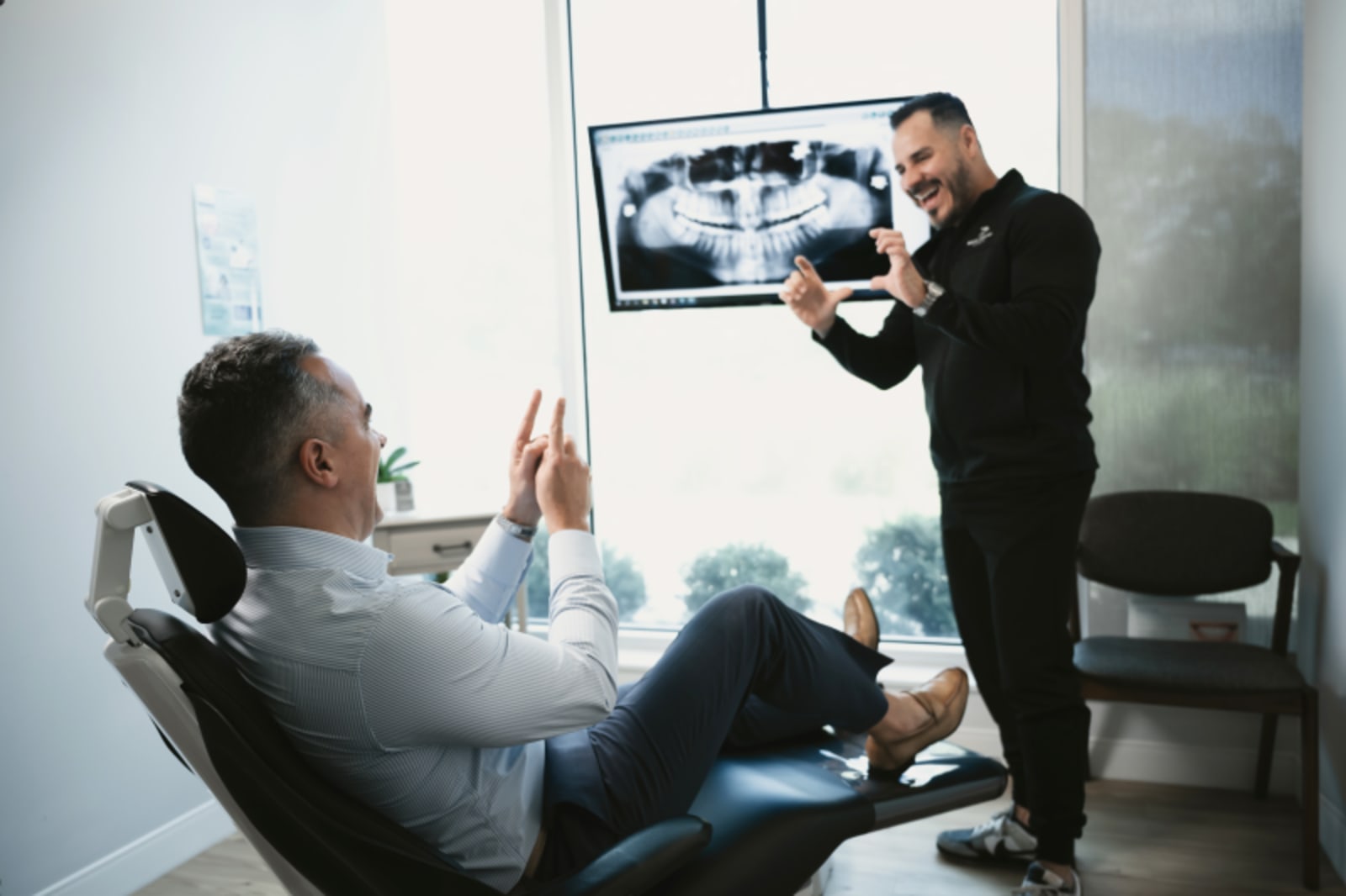 Dentist showing X-ray image to seated patient in treatment room