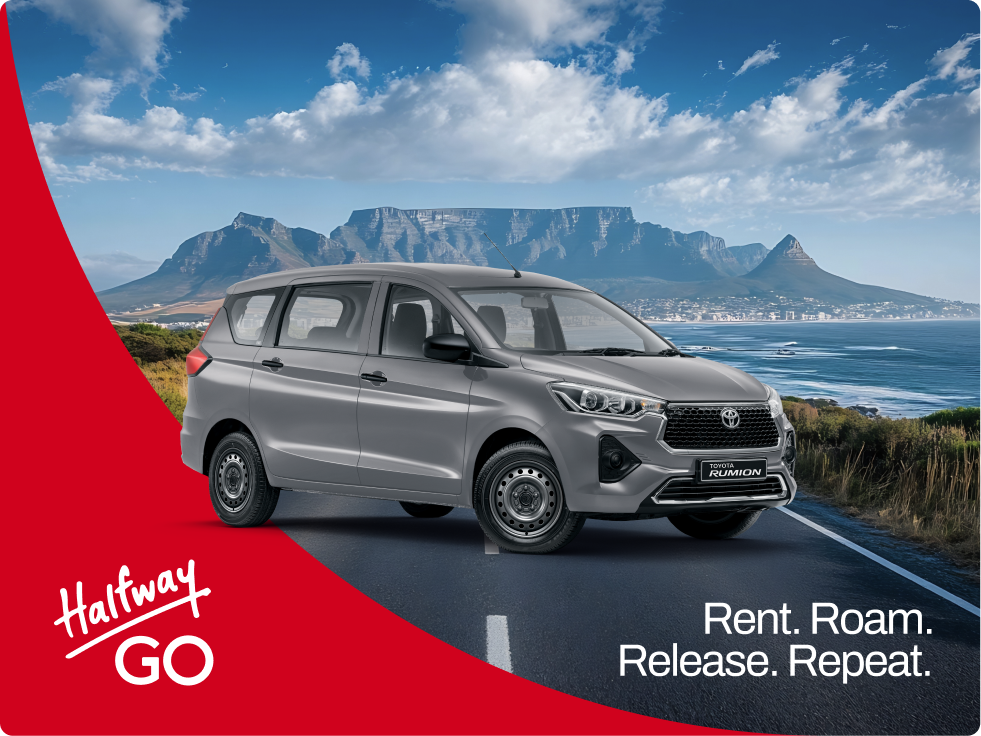 Silver Toyota Rumion car on a road with a scenic background of mountains, ocean, and blue sky with clouds, with text 'Halfway GO' and 'Rent. Roam. Release. Repeat.'