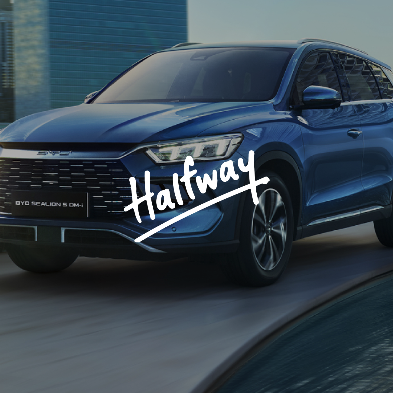 Blue BYD Sealion 5 DM-i SUV driving near curved water edge with modern buildings reflected on windows and 'Halfway' text overlay.
