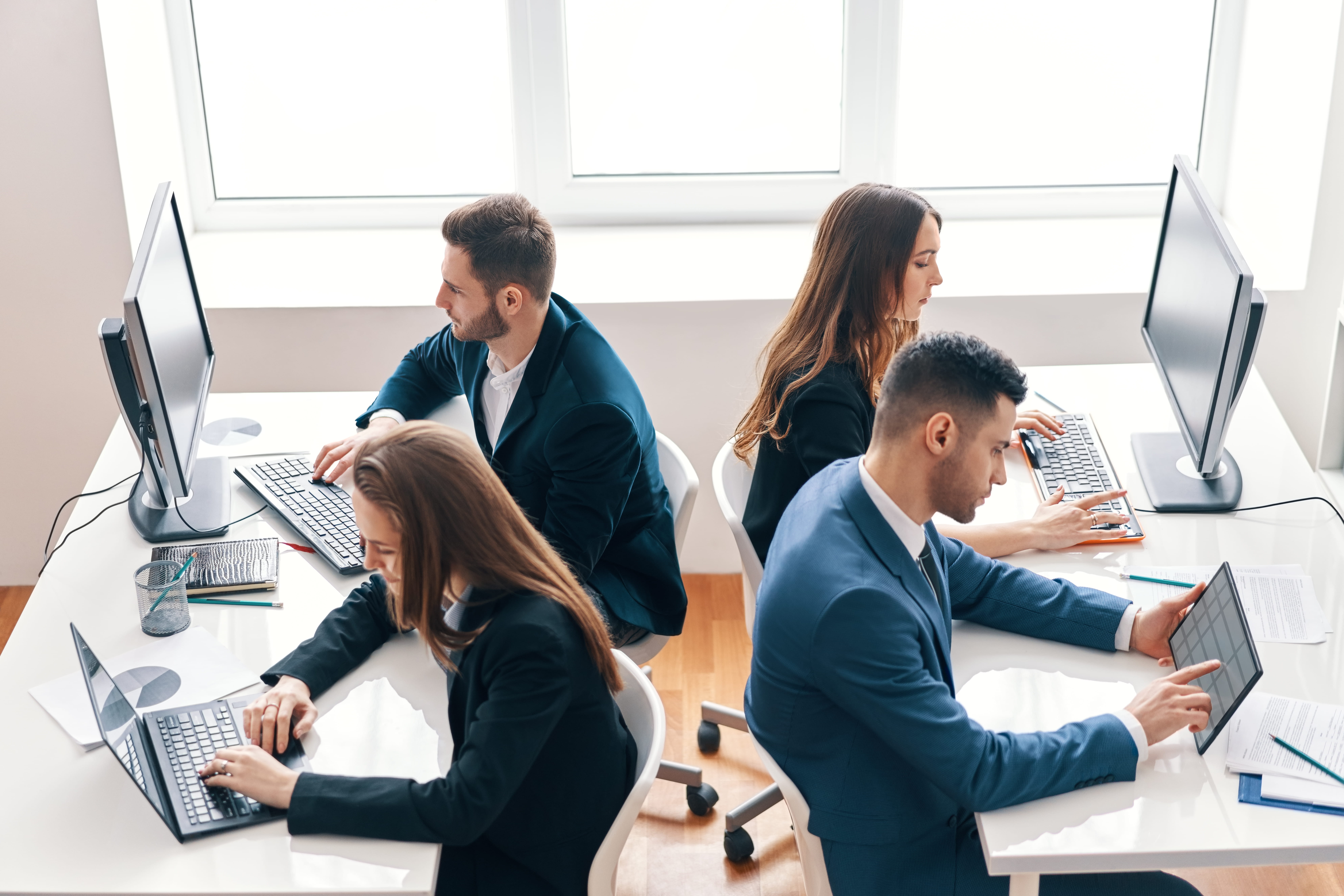 Employees across different departments working with AI tools at their desks in a modern office