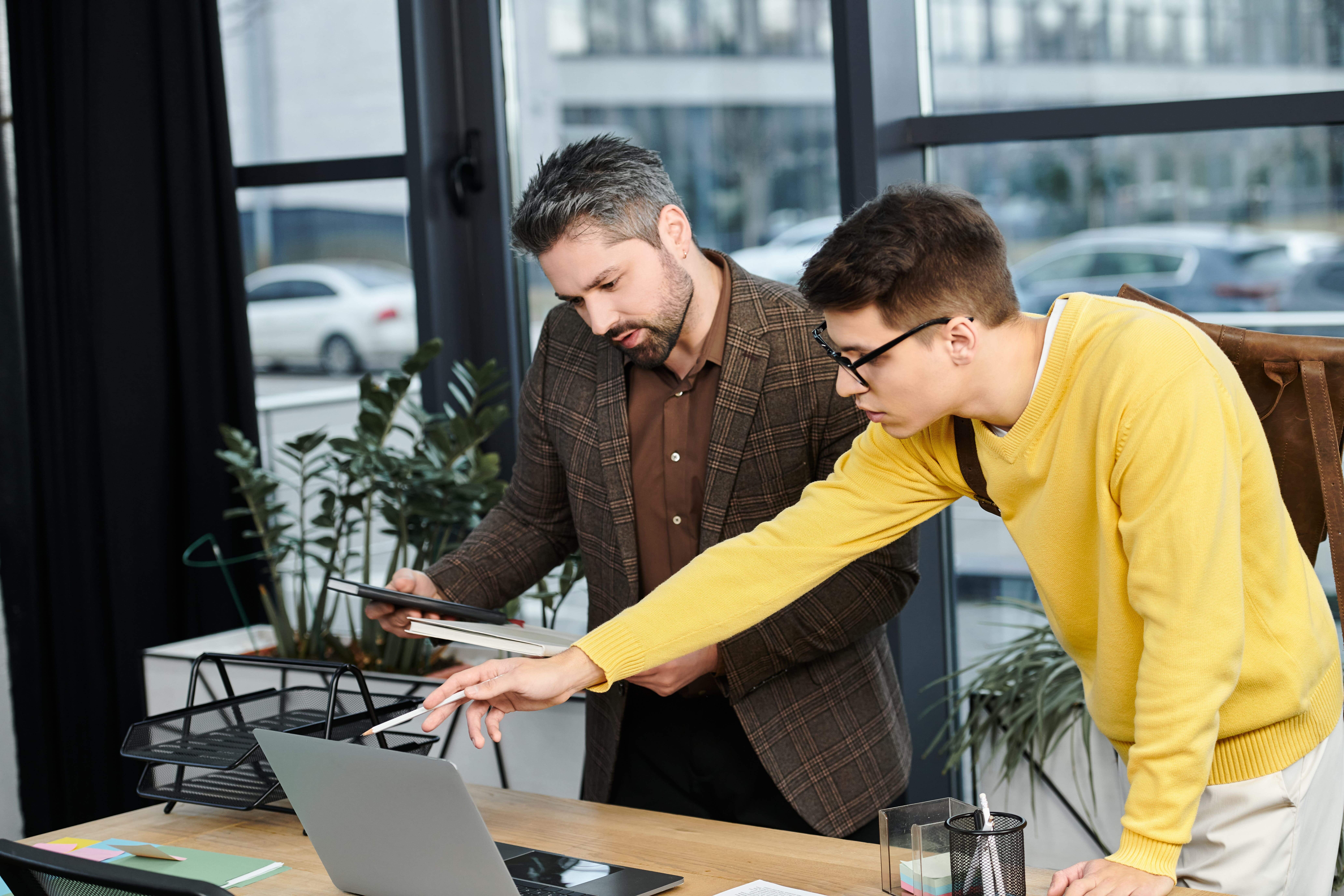 A peer champion helping a colleague use an AI tool at a laptop