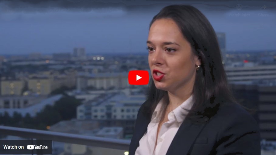 A young woman on a video with a cityscape in the background