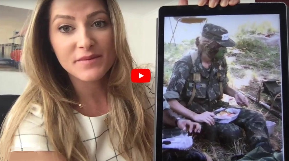 A young woman in a video holding a picture of herself as a soldier