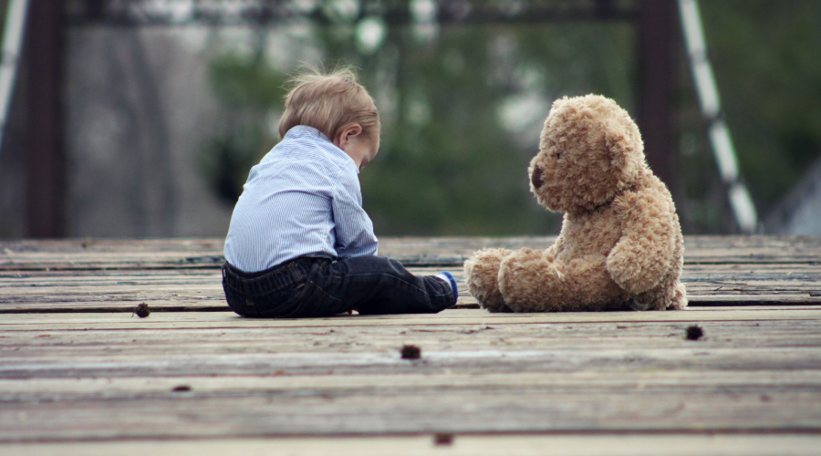 A toddler with a teddy on a bridge