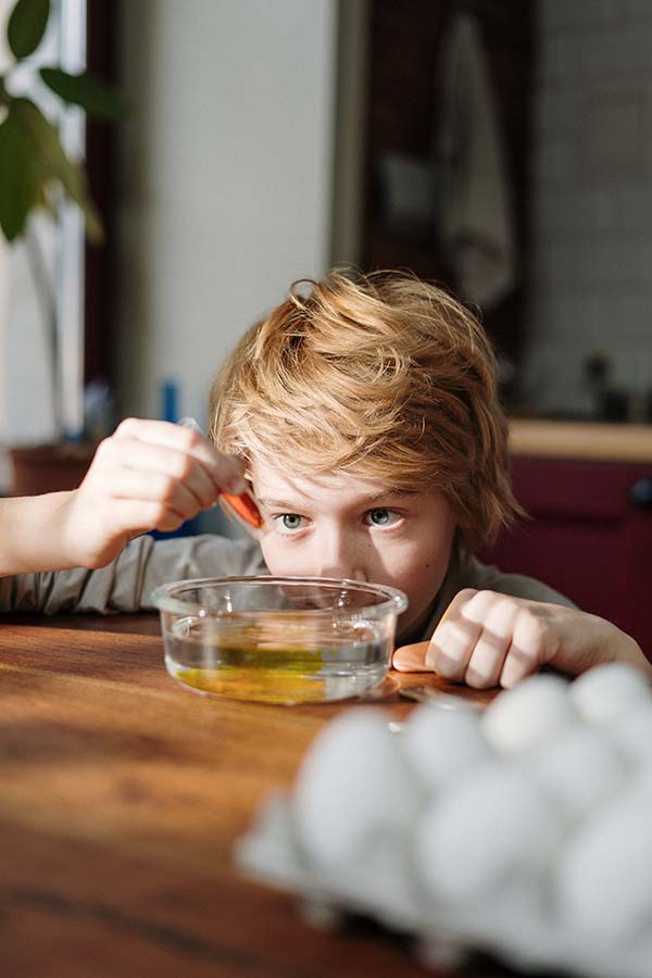 Boy playing with a bowl of water and red paint