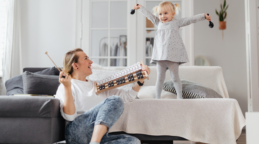 An early years educator and a preschool child play with instruments
