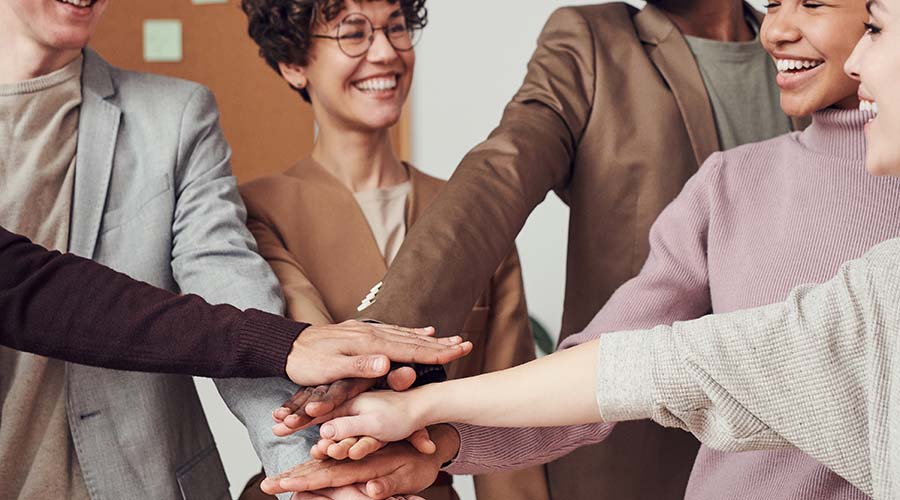 A group of Early Years educators in a circle doing the 'hands in' gesture together