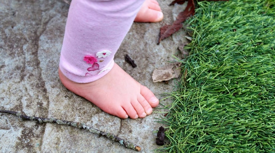 barefoot kid close to a grass patch