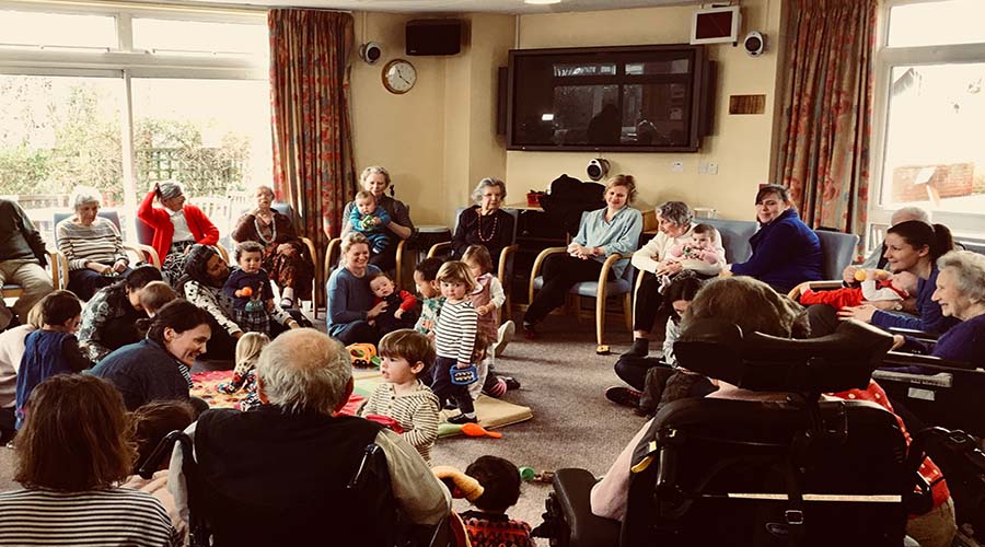 The baby and toddler group at Apples and Honey Nightingale. A large circle of elderly people in chairs with a smaller circle of toddlers and babies in the centre.