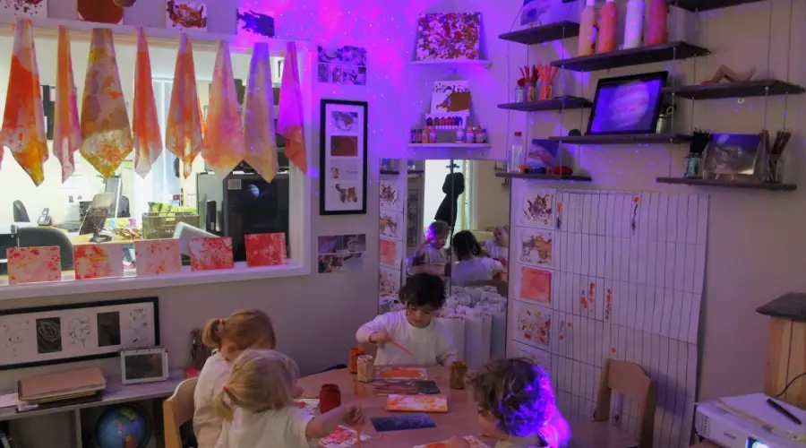 4 pre-schoolers at a Little Barn Owls nursery sit at a table and paint. 