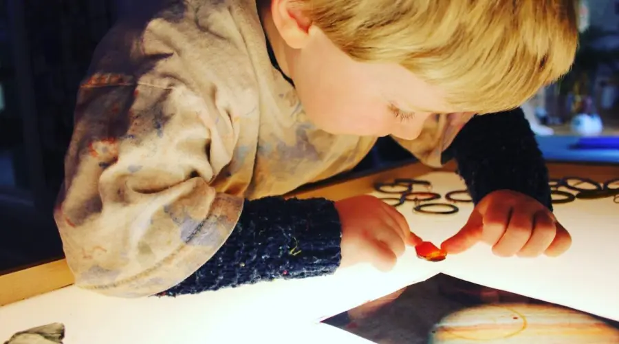A toddler at Little Barn Owls nursery explores resources on a light box