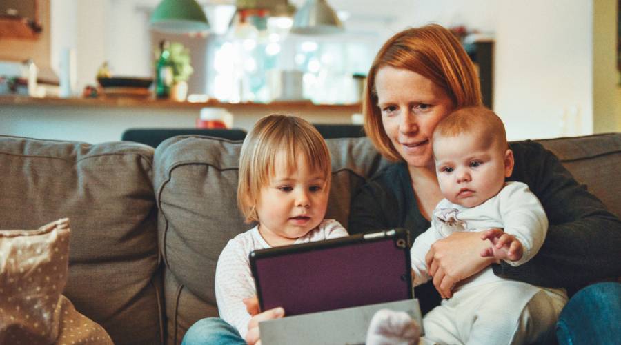 Mother with a toddler and baby reading on a tablet