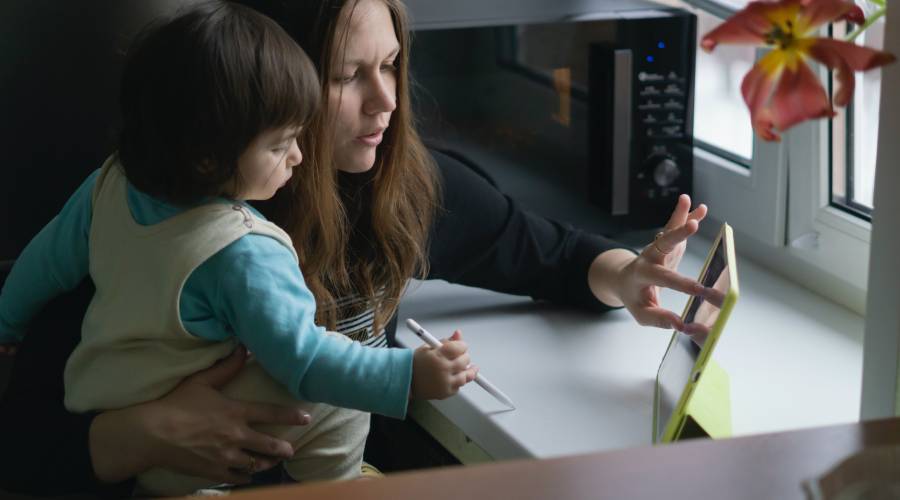 Mother and child working on a tablet by the window