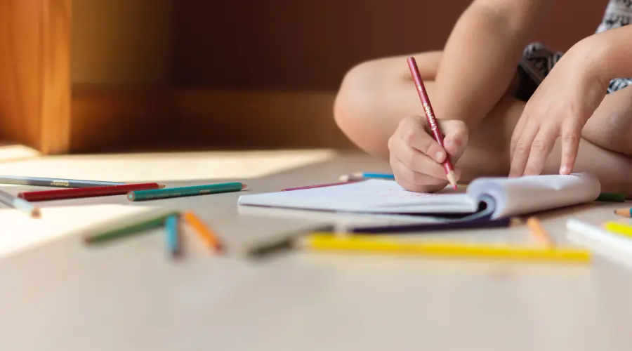 A young child's hand holding a pencil for mark-making
