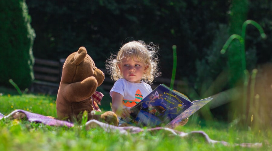 Girl sitting beside a teddy bear