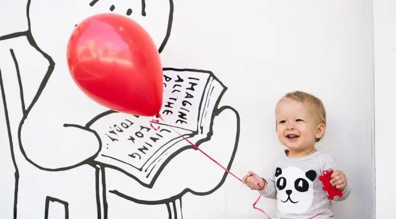 Small kid holding a red balloon