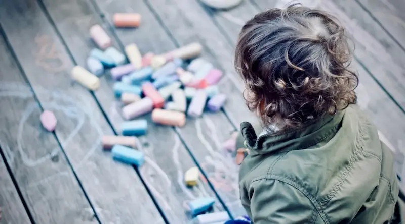 Child playing with chalk on the ground
