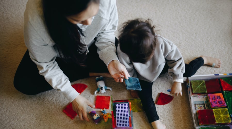 An Early Years educator plays with magentic tiles with a toddler