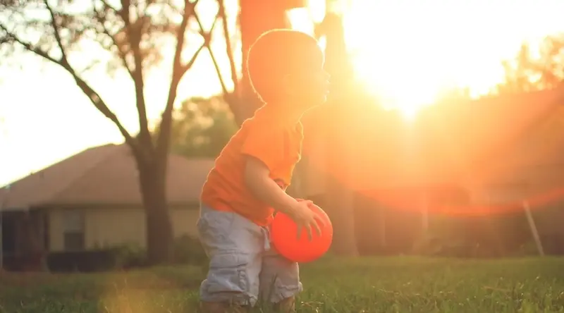 Boy playing with a ball at sunset