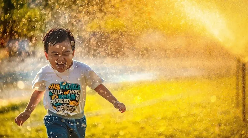 Boy playing with water outdoors on a hot day
