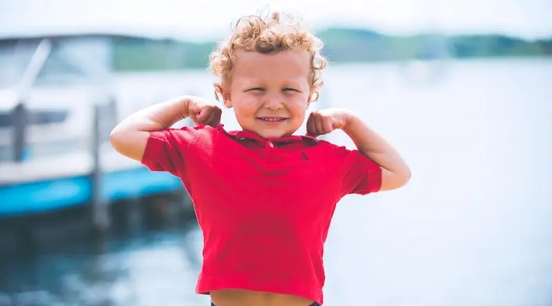 Curly boy in red t-shirt stretching on a pear