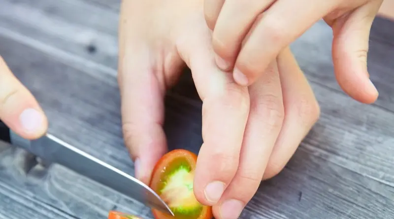 child helping adult cut tomato