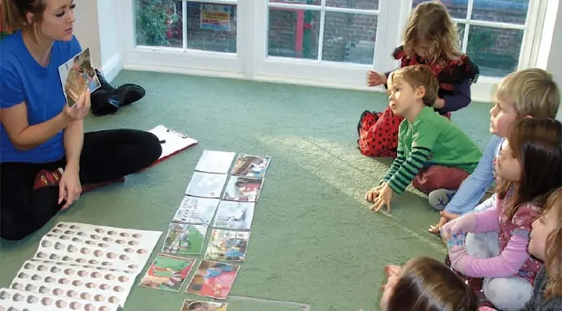 A group of children sitting on the floor, playing a board game with an educator.