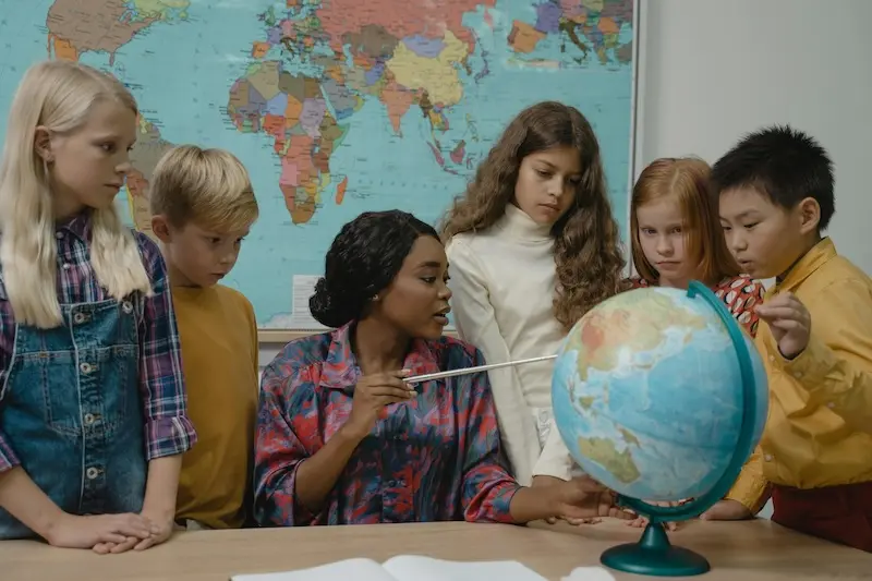 A teacher shows a class of young children a globe