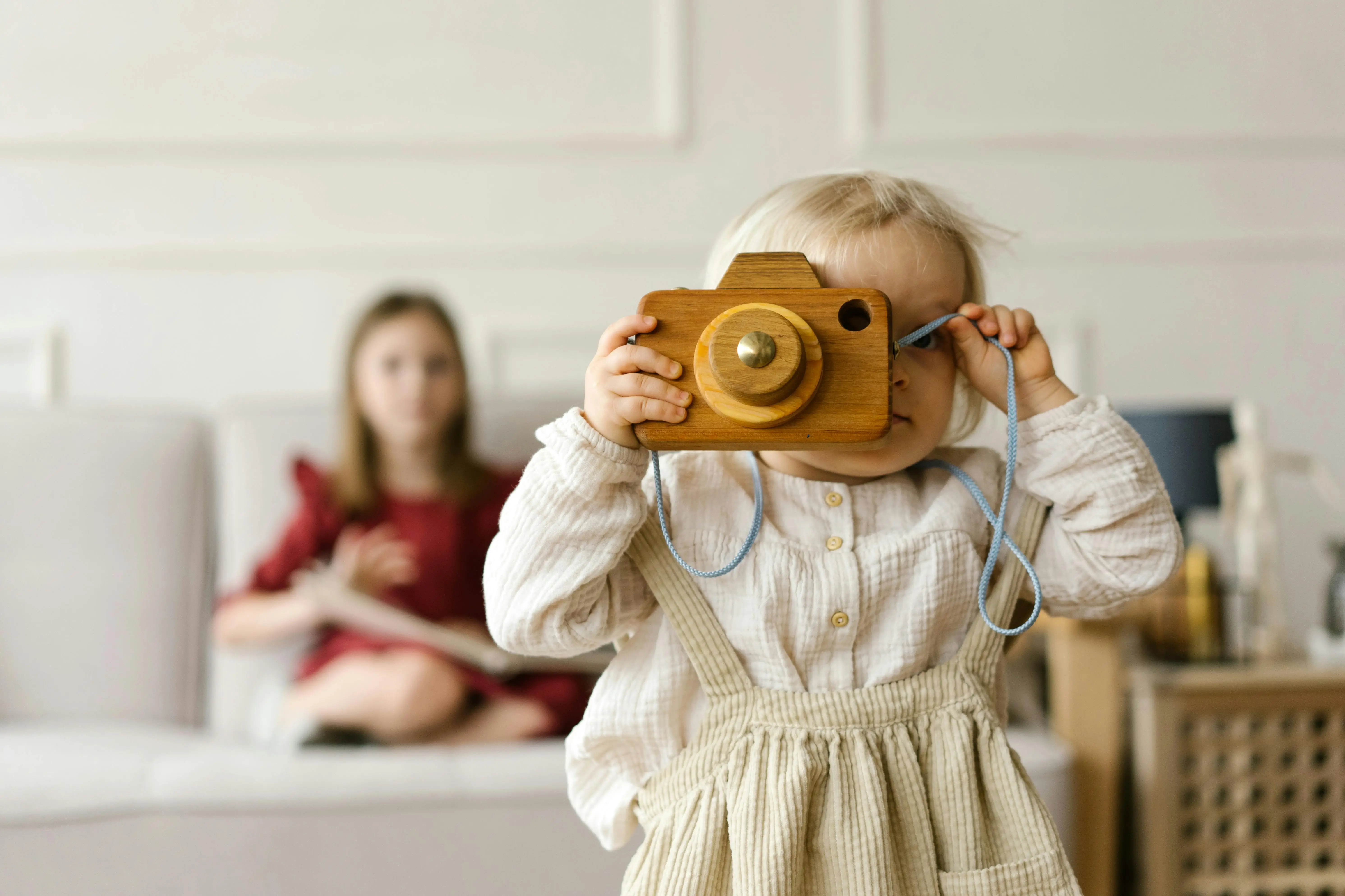 toddler playing with a wooden toy camera