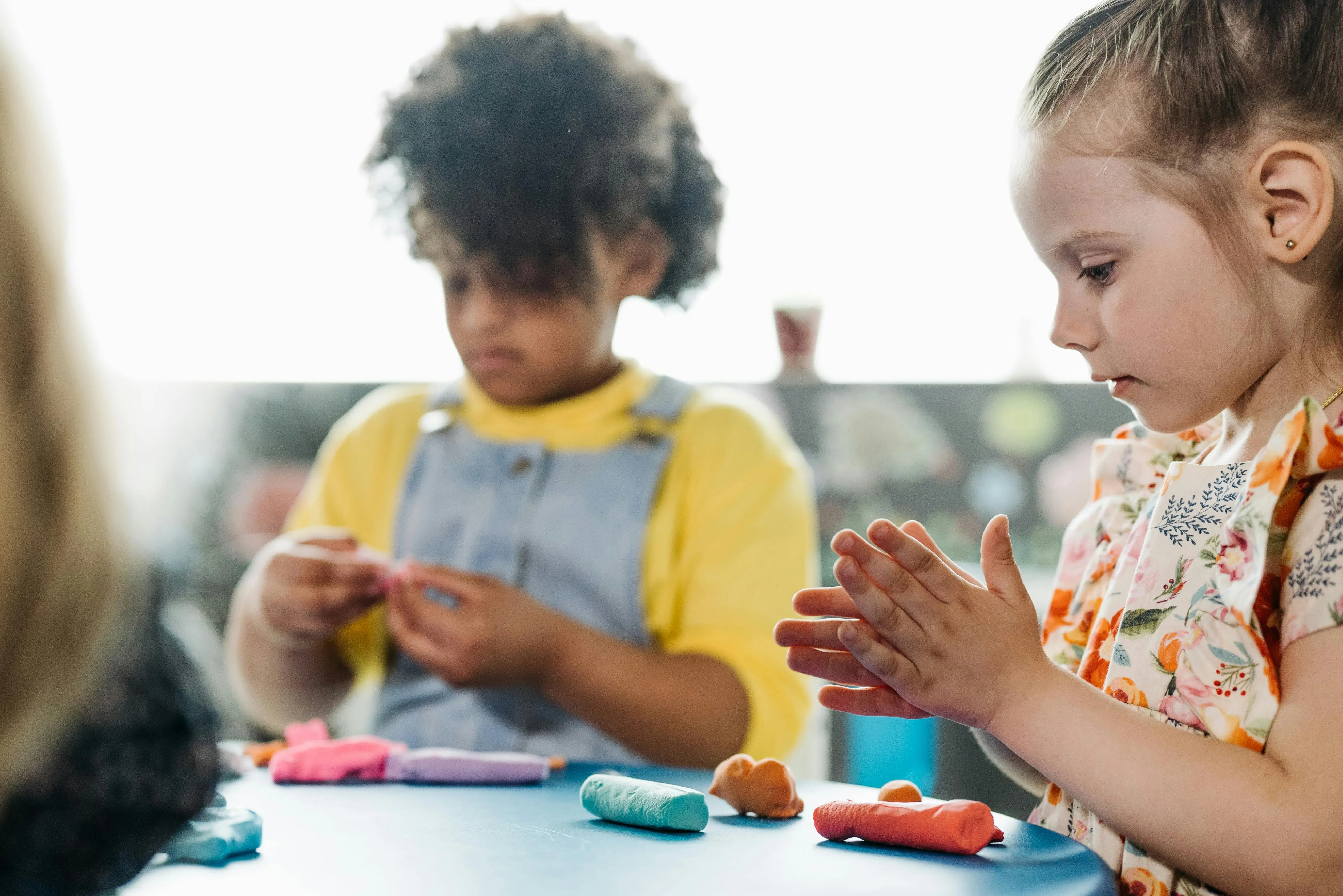 two girls in preschool classroom doing arts and crafts