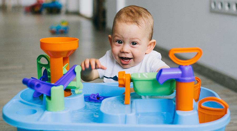 A baby plays with a plastic water play set