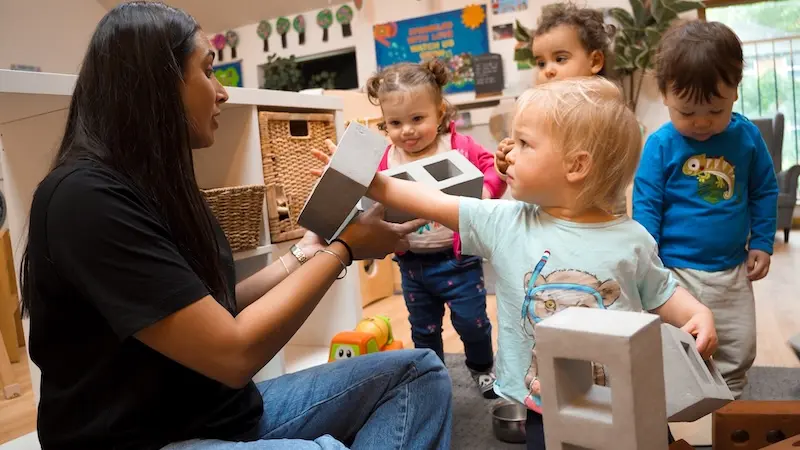 An Early Years manager plays with children in a nursery