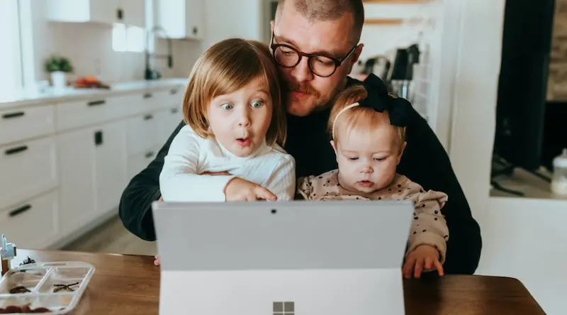 A father with his daughters looking at a tablet