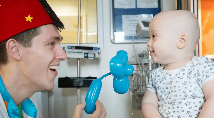 Dr Bungee holds up a balloon flower to a young patient n hospital