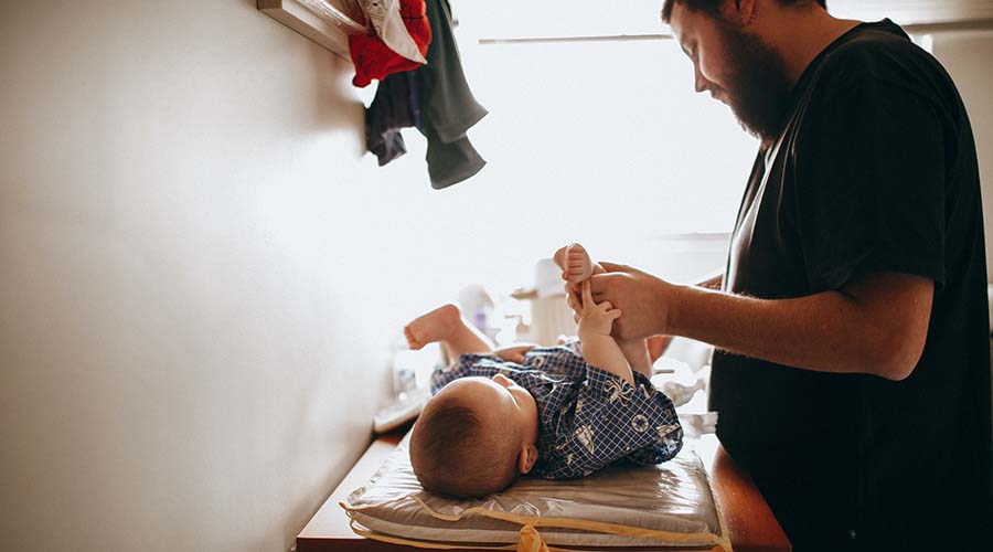 An educator is changing the nappy of a baby.