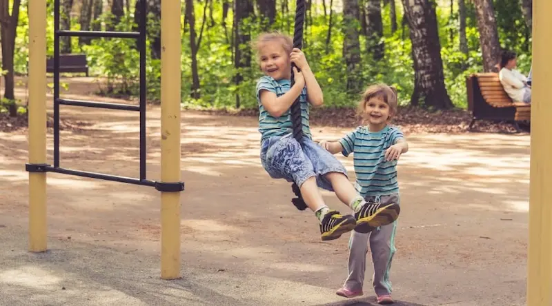 Two children playing together on the swings
