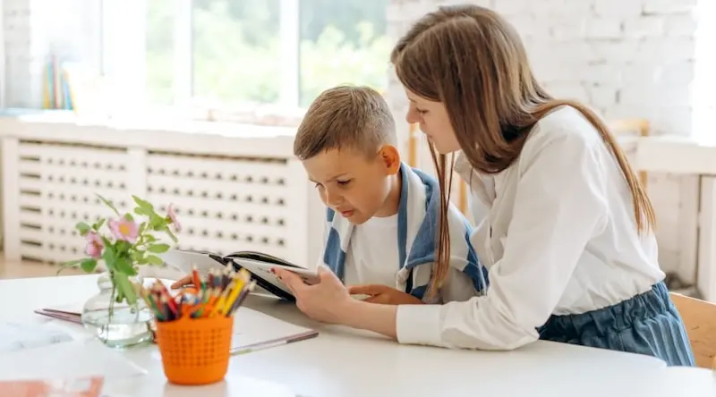 old sibling helping her brother to read